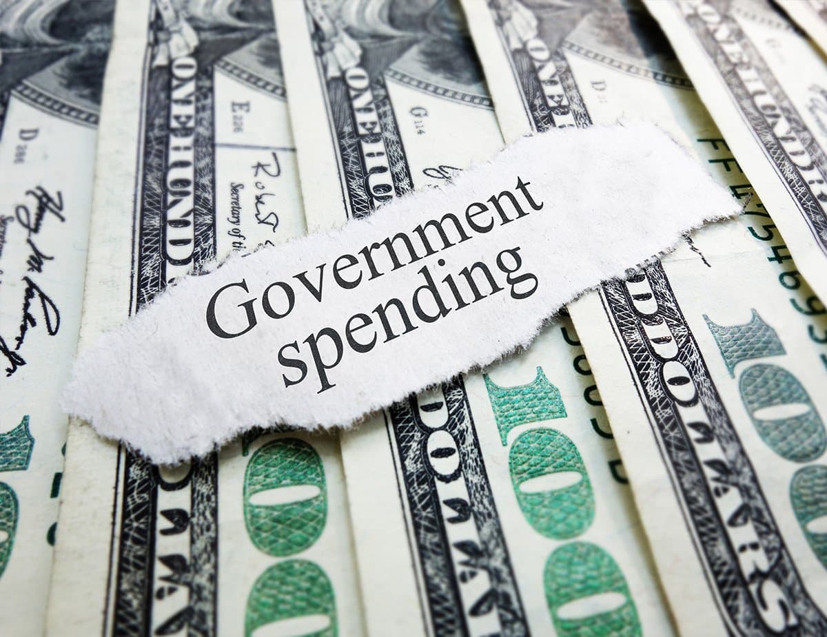 A torn newspaper headline reading “Government spending” over US banknotes